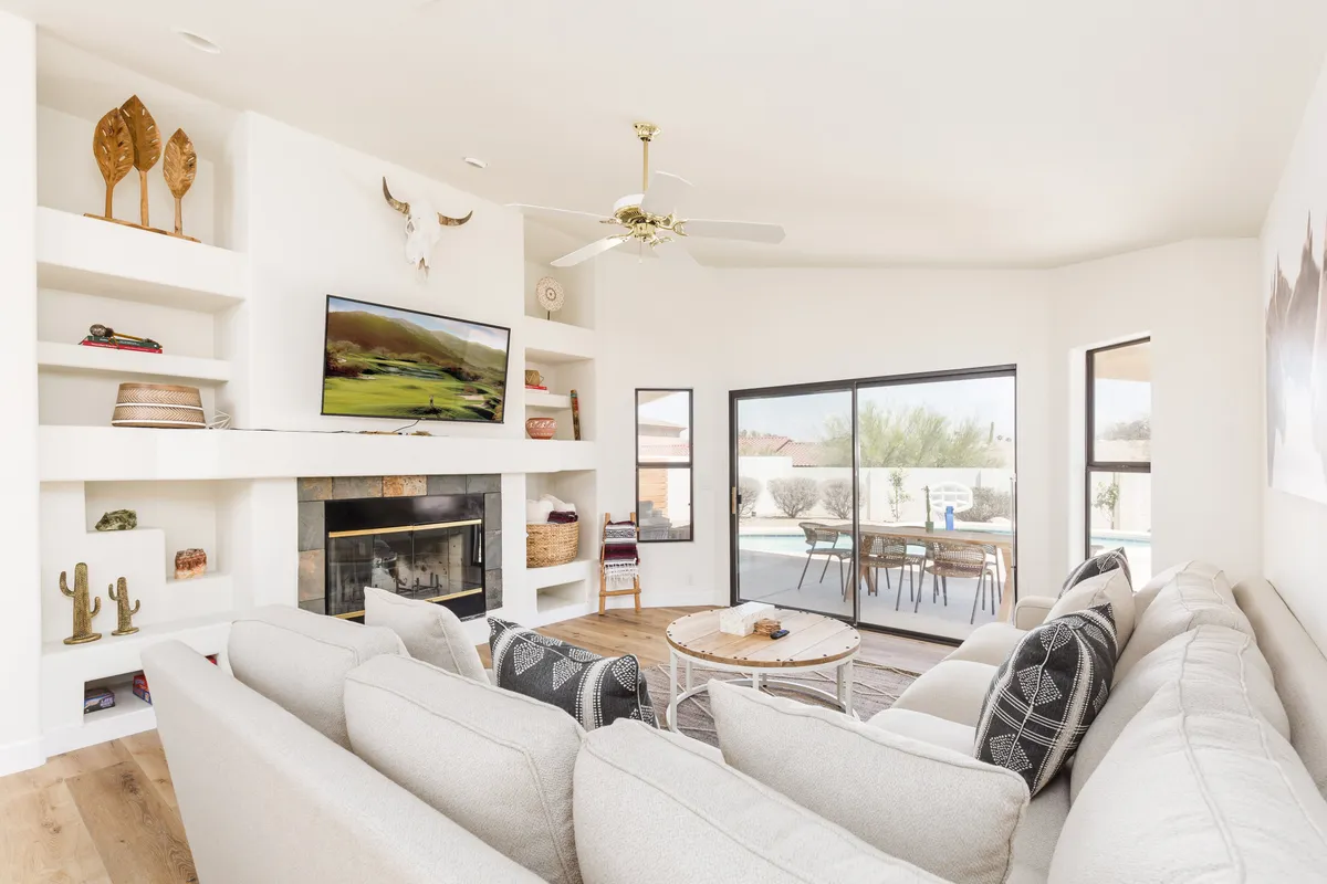 A spacious living area featuring a comfortable sofa, a fireplace, a large TV, a dining area, and decorative shelves. The layout exudes a welcoming, family-friendly atmosphere, ideal for gatherings, play, and relaxation. The decor is modern yet warm, with plenty of space for both children and pets.
