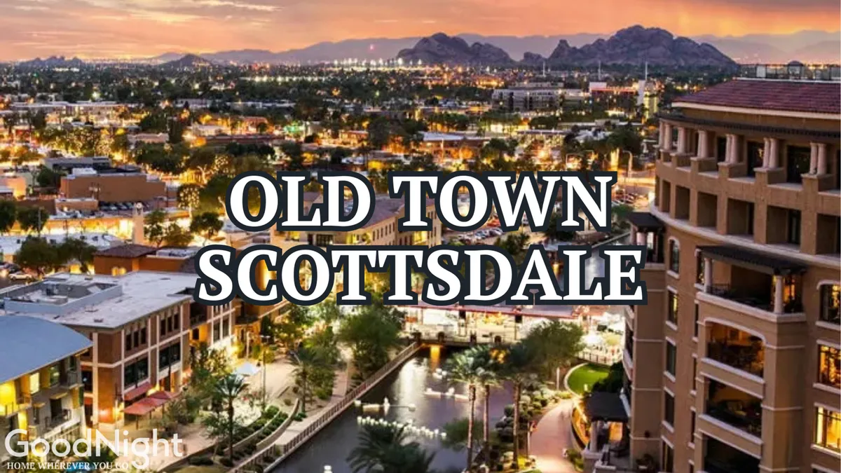 A vibrant view of Old Town Scottsdale at dusk, with illuminated signage, glowing buildings, a waterway running through the scene, and a mountain backdrop. The atmosphere is lively and welcoming, evoking the energy of Scottsdale's nightlife and entertainment options.
