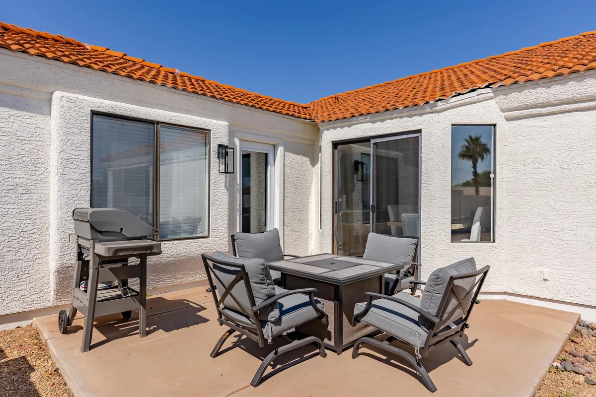 An outdoor dining space features a BBQ grill and a large dining table, set against the backdrop of surrounding privacy walls. The area is ideal for hosting alfresco meals and casual gatherings with friends and family.