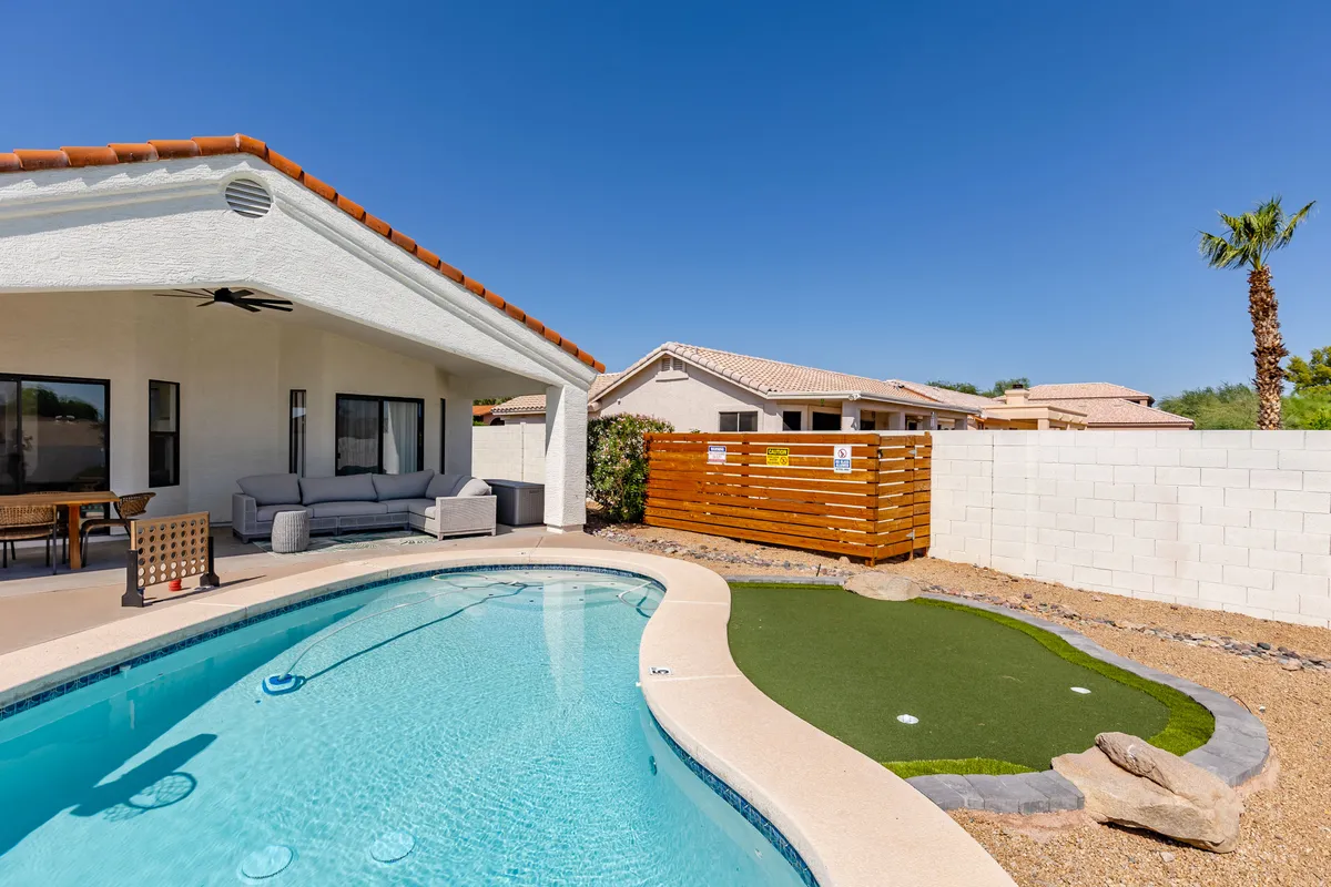 This photo highlights a backyard with a sparkling swimming pool, a cozy seating area, and, importantly, a putting green. The area buzzes with the promise of fun activities, from relaxing poolside to friendly putting competitions.